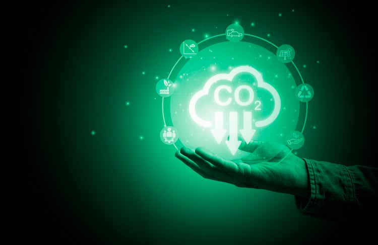 Hand holding CO2 reducing icon with environment symbol for decrease CO2 , carbon footprint and carbon credit to limit global warming from climate change, Bio Circular Green Economy concept.