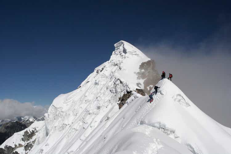Two climbers almost at the top of a snowy mountain top