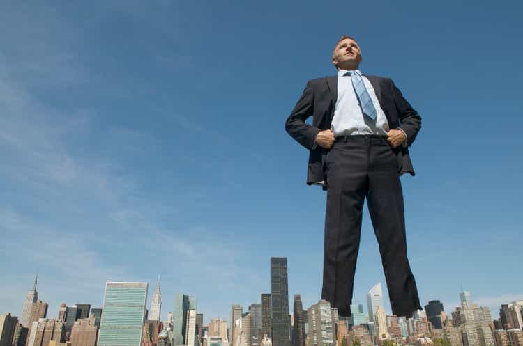 Confident Businessman Giant Towering Over City Skyline