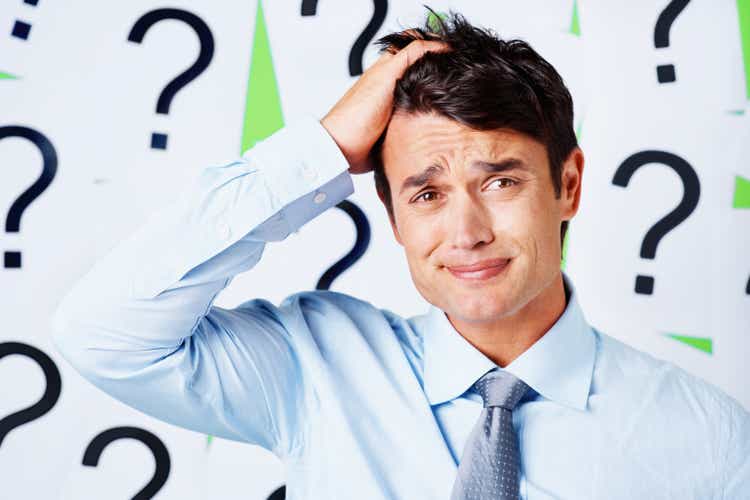 Stressed out business executive against question mark signs