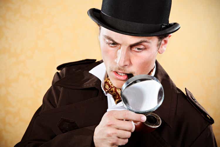 Sherlock Holmes with hat, trenchcoat, and magnifying glass