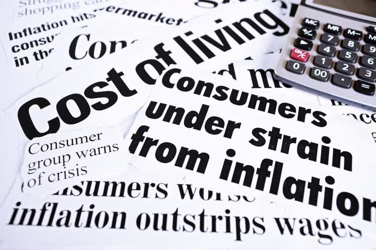 Calculator on newspaper headlines about cost of living and inflation