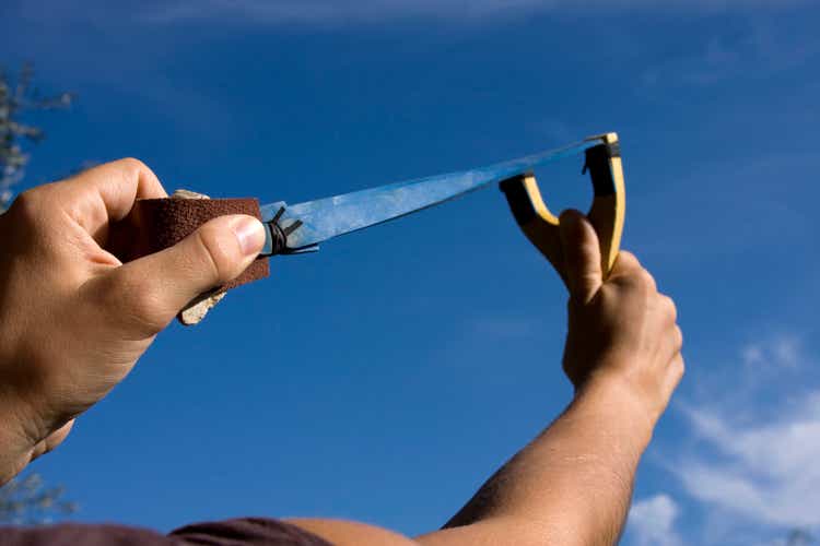 A rock is pulled back in an sling shot pointed to the sky