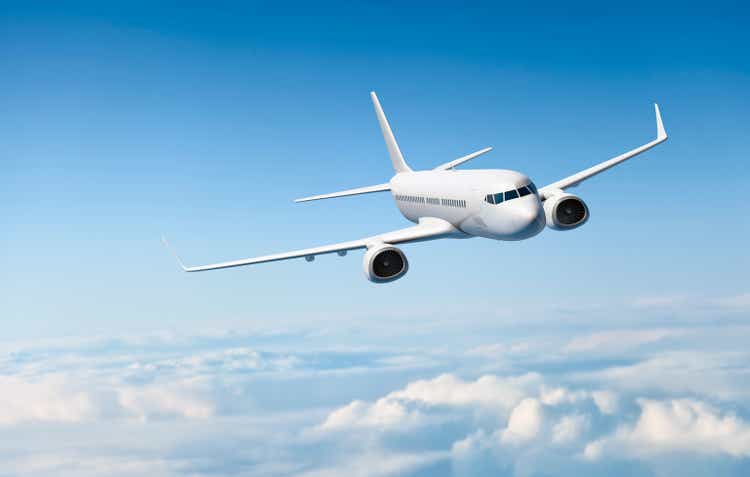 White passenger aircraft flying over clouds