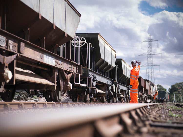 Railway worker wearing high visibility clothing waving alongside train