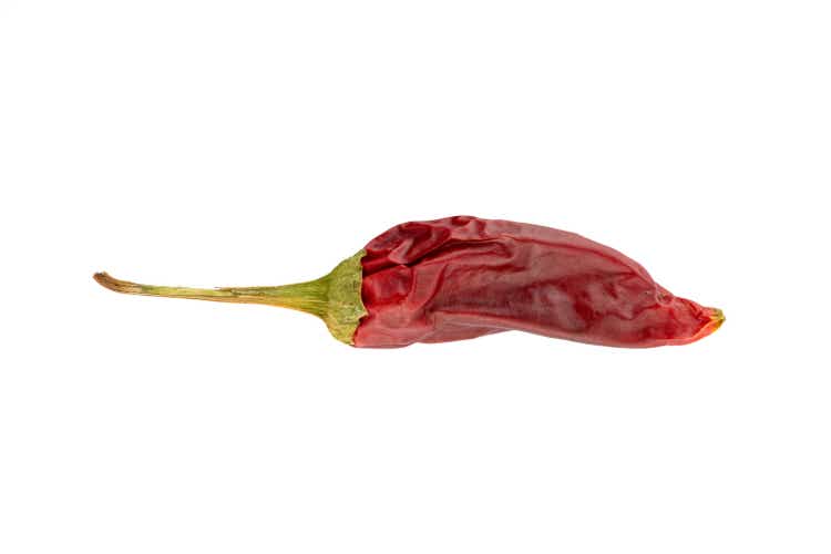 Single dry red chili pepper on white