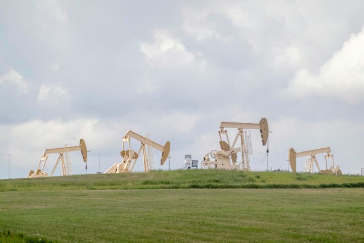 Several crude oil production wells, a site with pump jacks in a rural area during summer in Alberta Canada. Concept: Oil and gas emissions