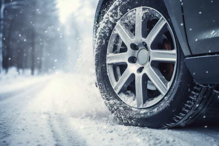 Car on winter tires drives through a snow-covered road.