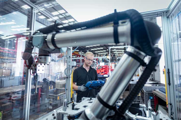 Worker working with cobot, robot assembly machine in automotive parts factory