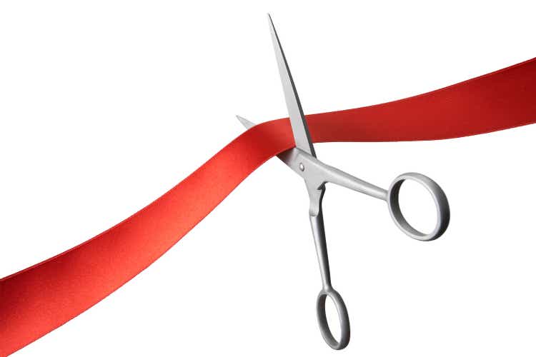 Pair of scissors cutting a red ribbon