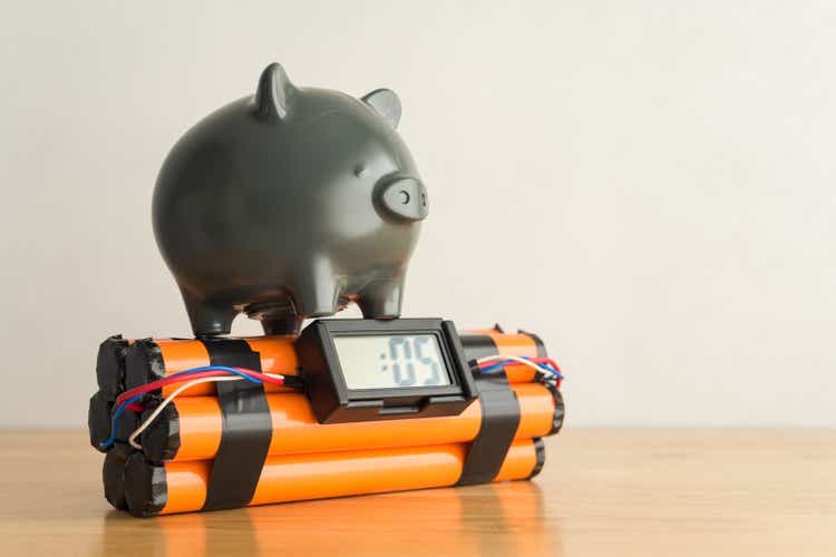 Piggy bank on time bomb wooden table with white wall background copy space.