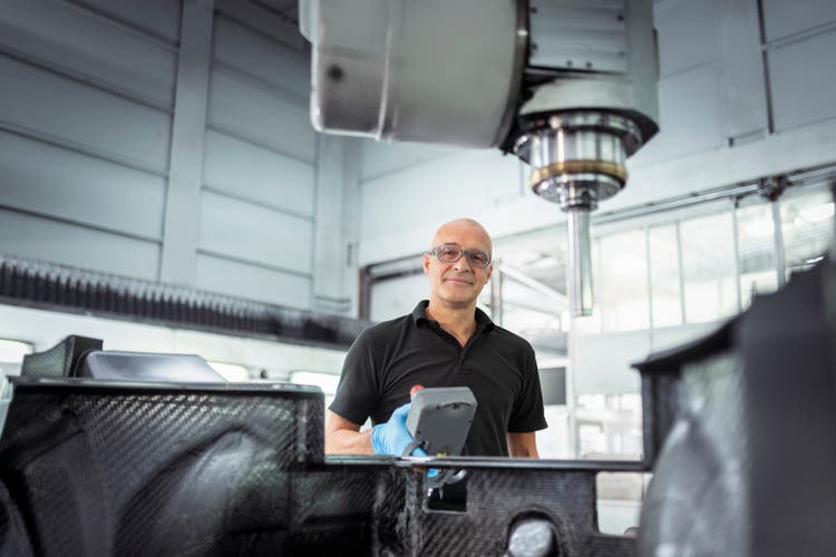 Engineer using lathe to cut carbon fibre automotive parts in automotive parts factory