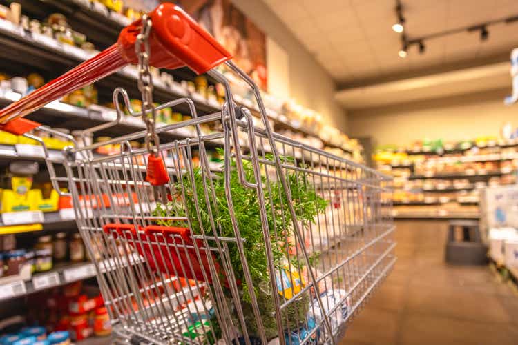 Carrito de compras en el supermercado con comestibles - Foto de archivo