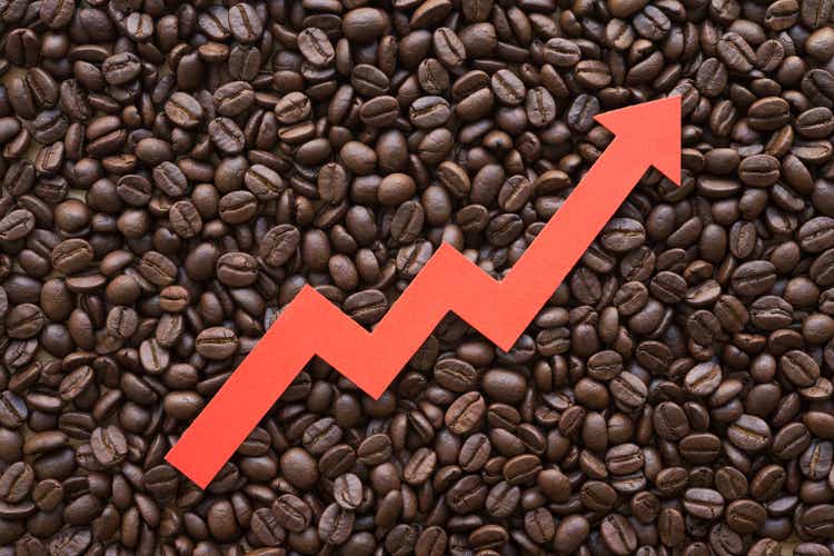 Red arrow chart graph soar rising up on coffee roasted arabica bean background.