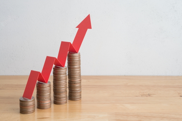 Stack of coins bar chart and red graph growing up with white wall background copy space.