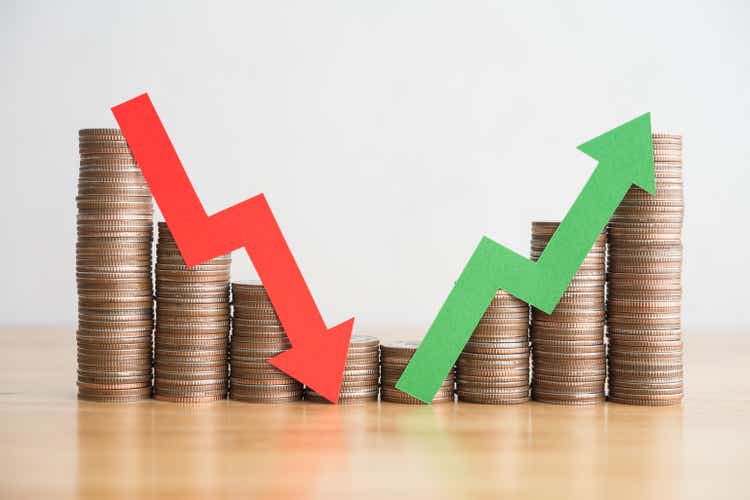 Stack coins and arrow red green graph chart volatility up and down on wooden table background.