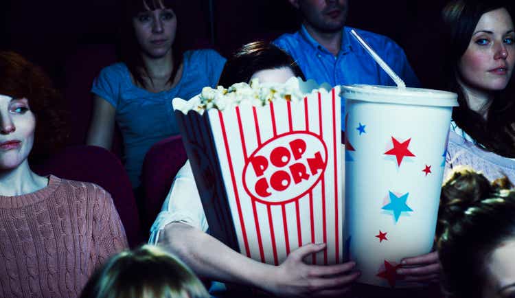 Woman holding giant sized popcorn and drink