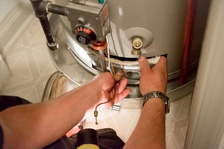 Man shines flashlight on hot water heater