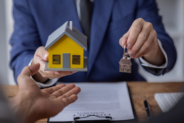 Sale agent giving house key to new client after signing agreement contract with approved property application form, mortgage loan Home Insurance and Real estate investment concept,