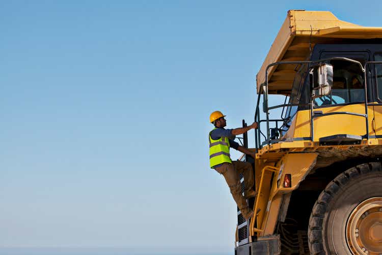 Worker climbing machinery on site