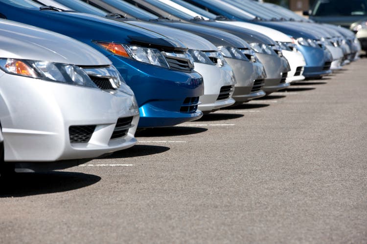 Line of new compact cars at dealership.