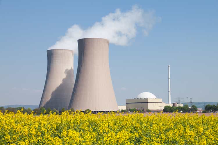 Nuclear power station with steaming cooling towers and canola field