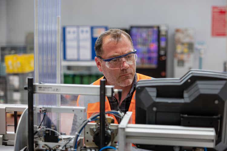 Male industrial worker working with manufacturing equipment in factory