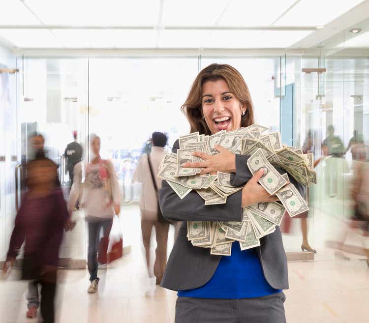 Hispanic businesswoman holding armful of dollar bills