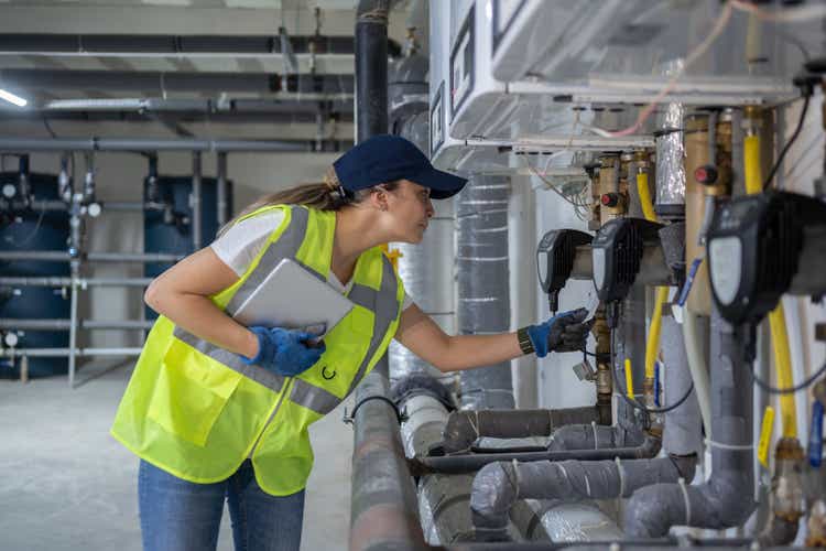 Female Engineer Checking Boiler System In A Basement