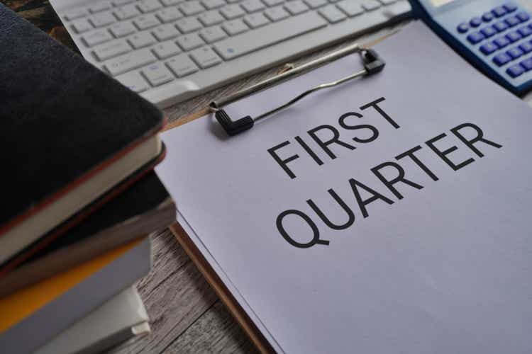 Paper clipboard with text FIRST QUARTER on office desk