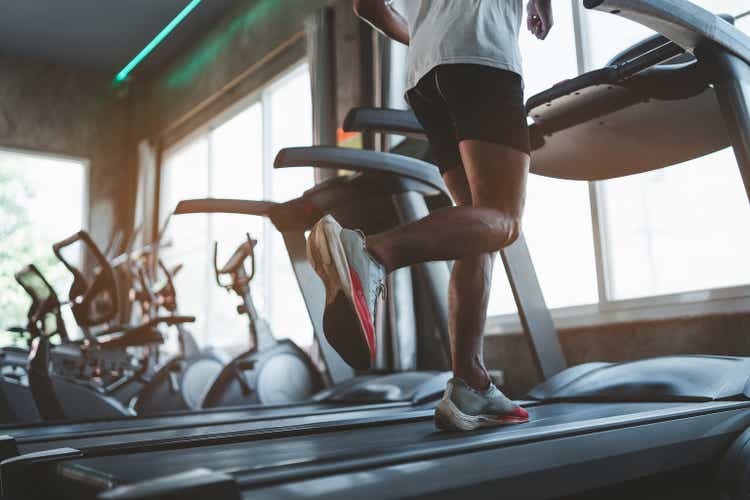 Close up of feet, sportman runner running on treadmill in fitness club. Cardio workout. Healthy lifestyle, guy training in gym. Sport running concept