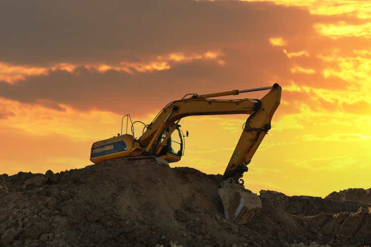 Excavator on earthmoving at open pit mining. Backhoe dig sand, gravel in quarry on sunset. Geology