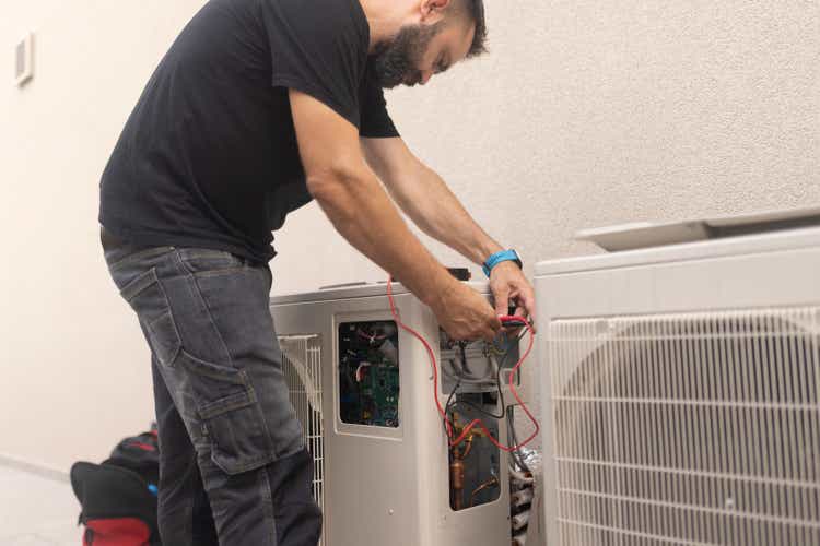Concentrated man installing a heat pump in the yard, which is very good for households because it increases energy savings