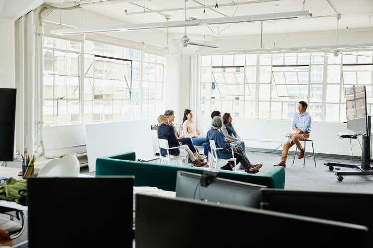 Wide shot colleagues in project meeting in conference area in office