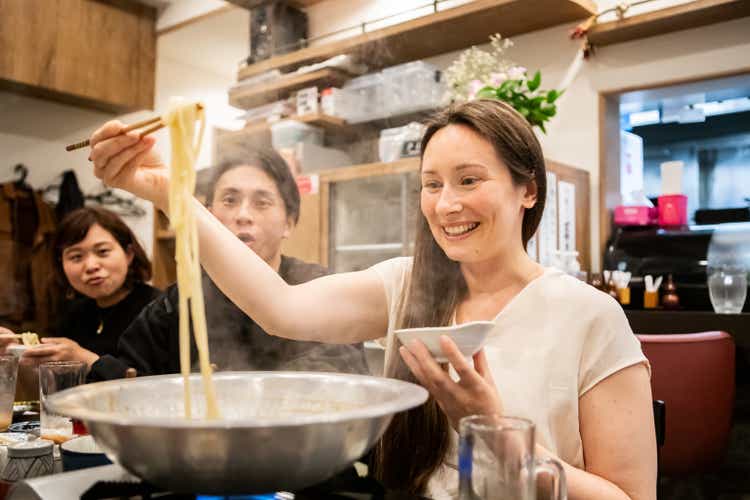 Tourists from overseas try eating udon at a Japanese izakaya.