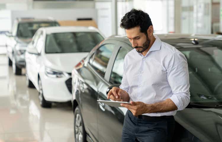 Car salesperson working at the dealership using a digital tablet