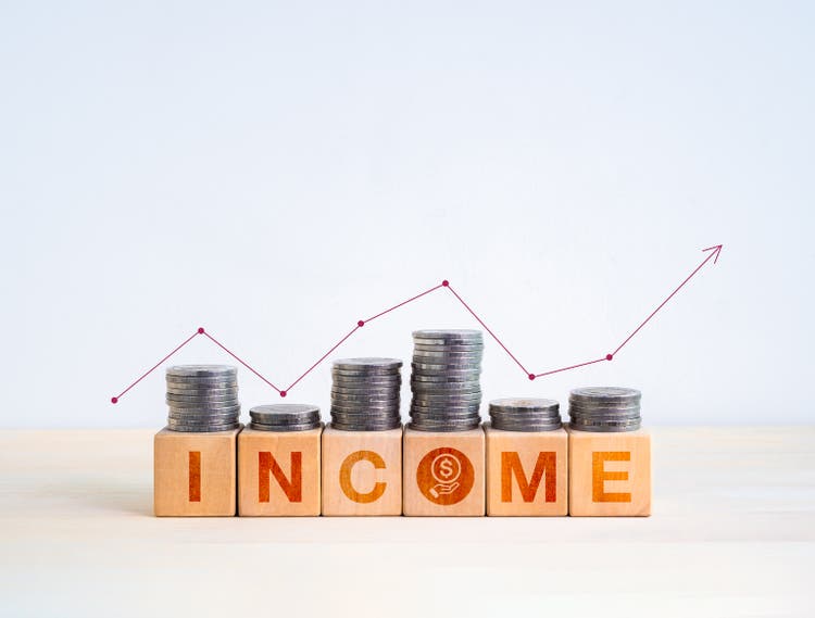Investment, income, savings and balance concept. Text INCOME with get money icon on wooden cube blocks with coins stacks and line graph on the top, isolated on white background with copy space.