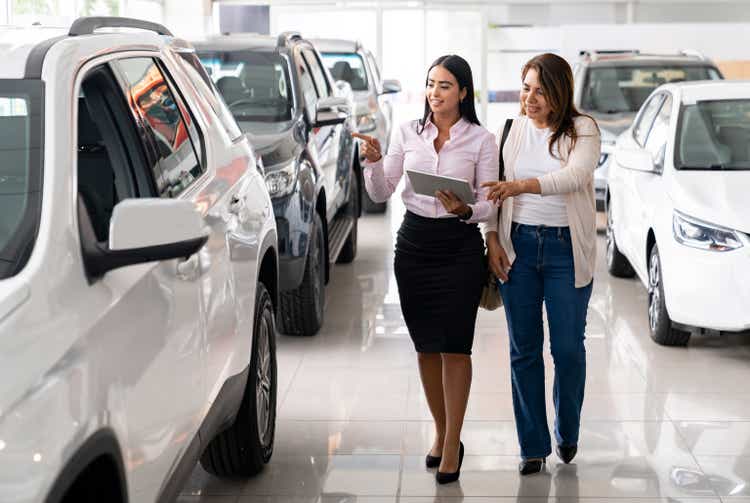 Salesperson showing a car to a woman at the dealership