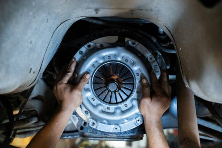Mechanic"s hand installing new clutch plate in car, clutch system,