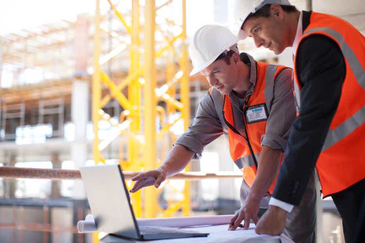 Construction workers using laptop on construction site