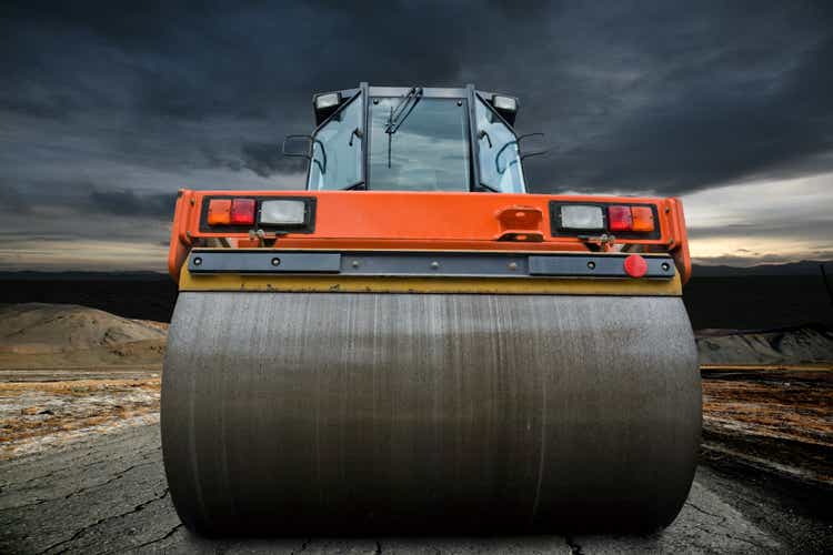 Big orange road roller upon a cloudy sky