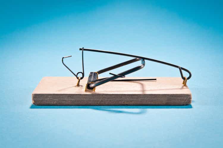 Single wooden mousetrap isolated on blue, side view, studio shot