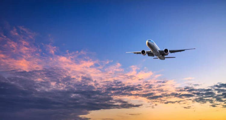 Big airplane leaves the ground in the sky at sunset