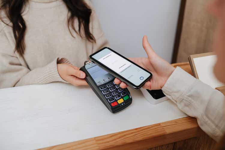 A girl paying contactlessly by touching her phone to the payment terminal