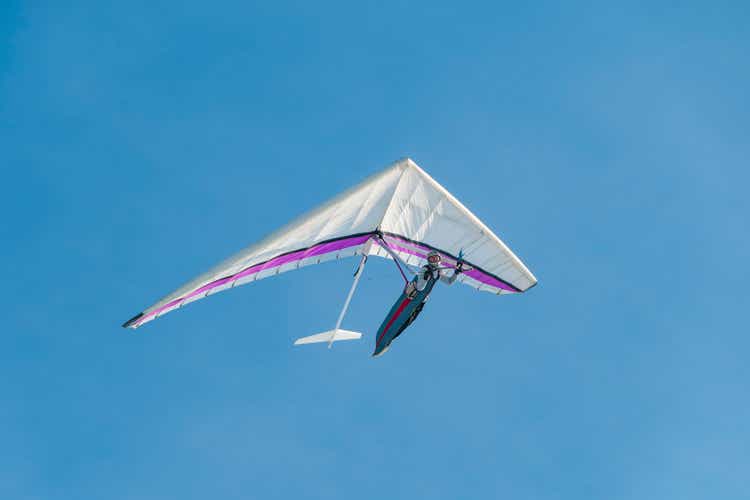 Hang glider pilot soaring in the blue sky.