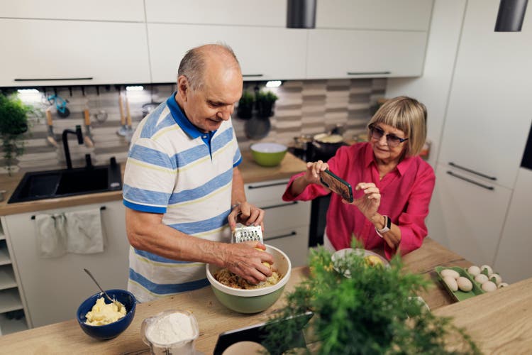 Senior couple making an apple pie in modern kitchen