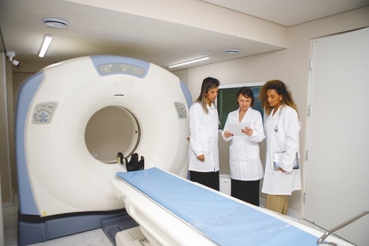 Un equipo de médicos analiza el diagnóstico junto a una máquina de resonancia magnética