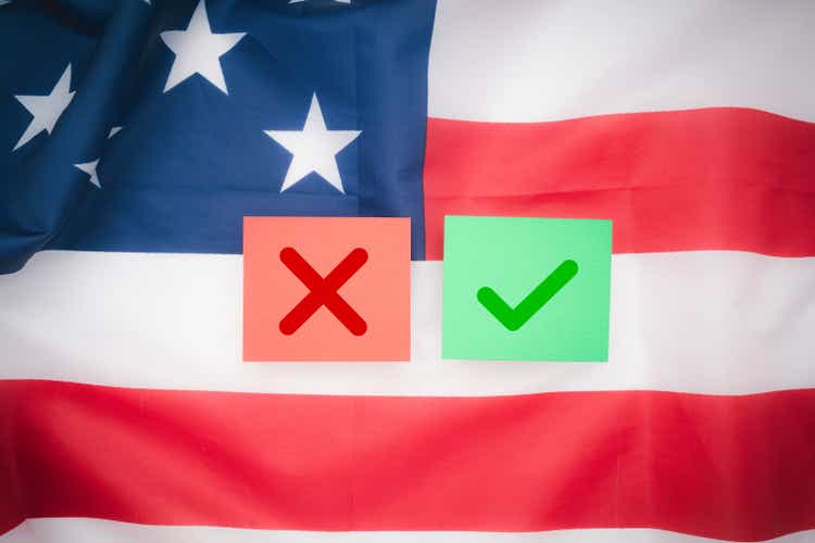 Two pieces of paper with a green check mark and a red cross on the background of the American flag