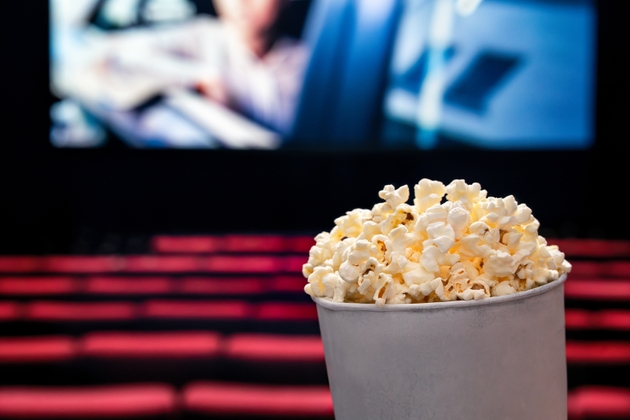 Movies and popcorn. Pop corn at cinema. Family film night concept. Action or romantic comedy entertainment on screen. Dark theater with red seats. Salty snack in bucket or box.