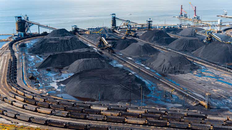 Cargo coal transportation as Global Business in Newport News, VA port. Wet coal heaps surrounded by cargo containers on railroad. Aerial view